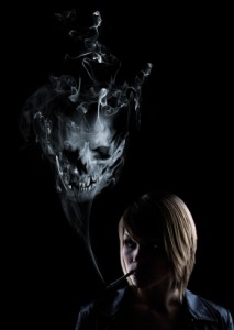 Young women smokes a cigarette and in the smoke appears a deadly skull.